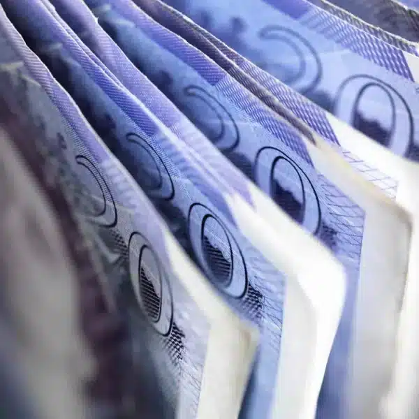 Close-up, angled view of blue UK pound banknotes fanned in a stack.